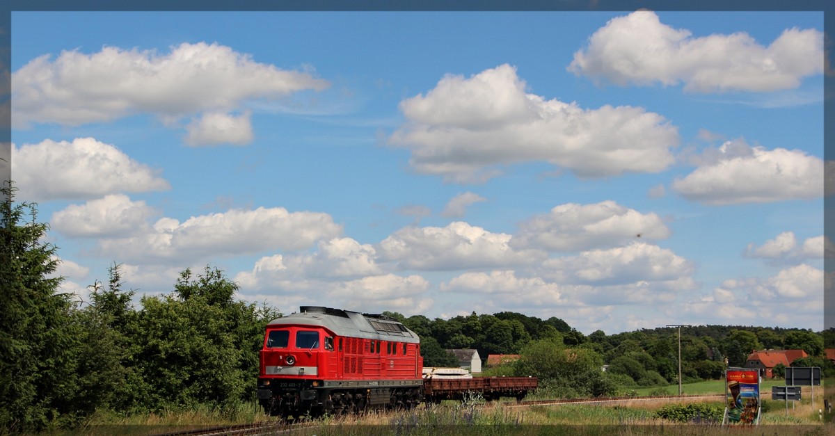 232 469 mit ihrem grenzlastigen Zug in Klein Plasten am Bahnübergang in Richtung Kargow (Meckl.) aus Möllenhagen kommend am 30.06.2015